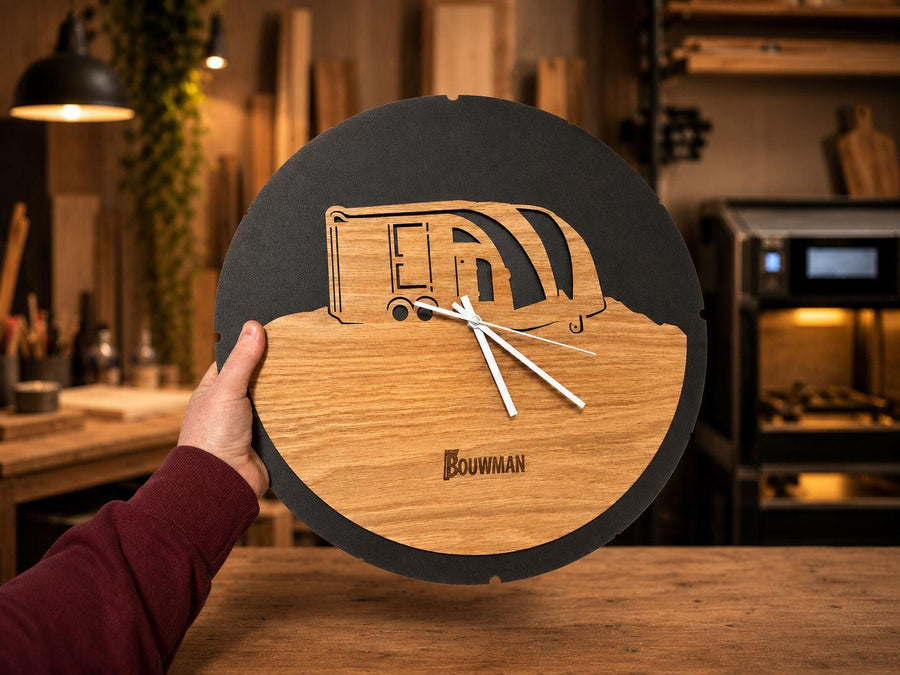 Ronde houten klok met een nagetekende caravan en de naam Bouwman erin gegraveerd